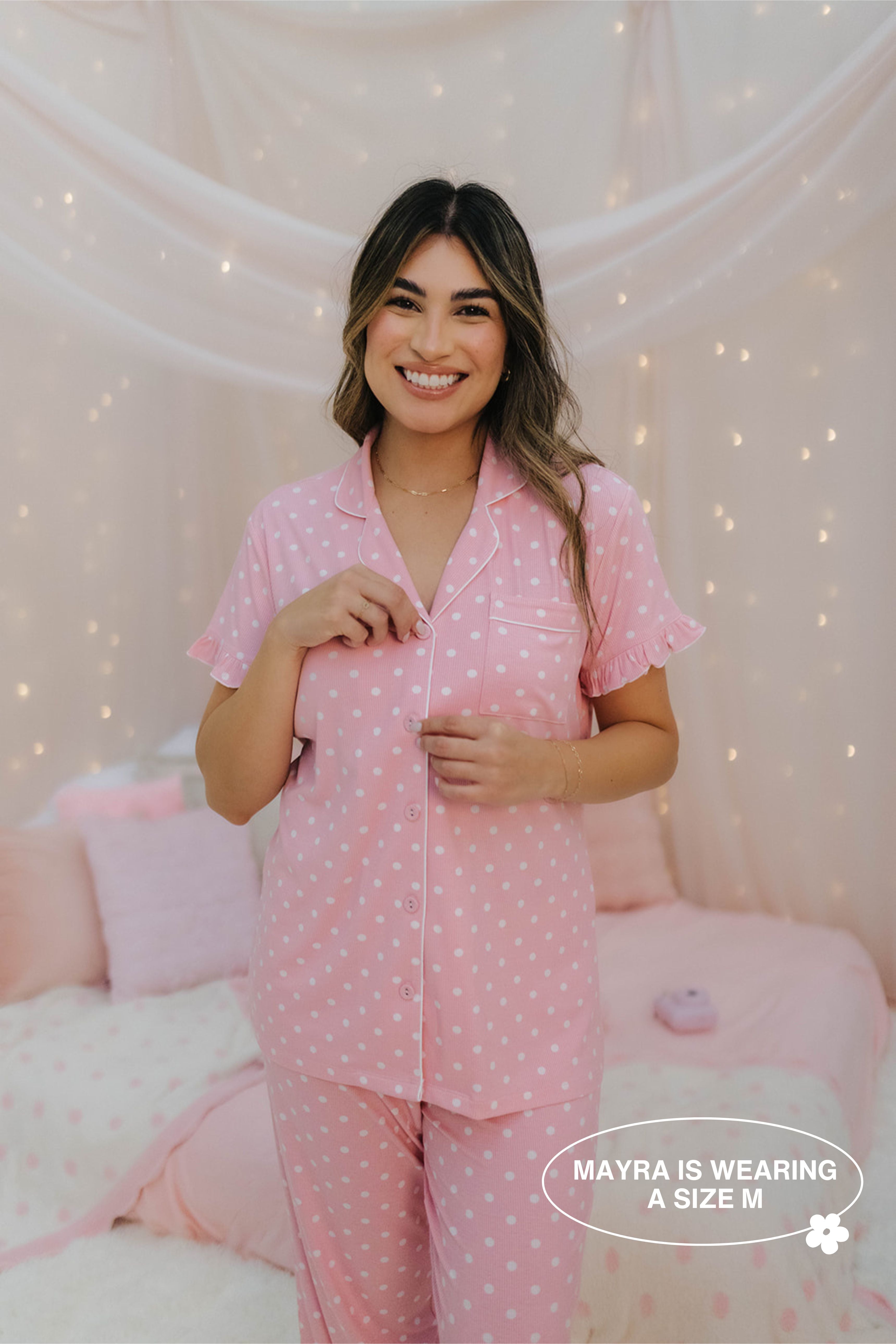 Woman wearing pink polka dot pajamas in a cozy room with soft lighting.