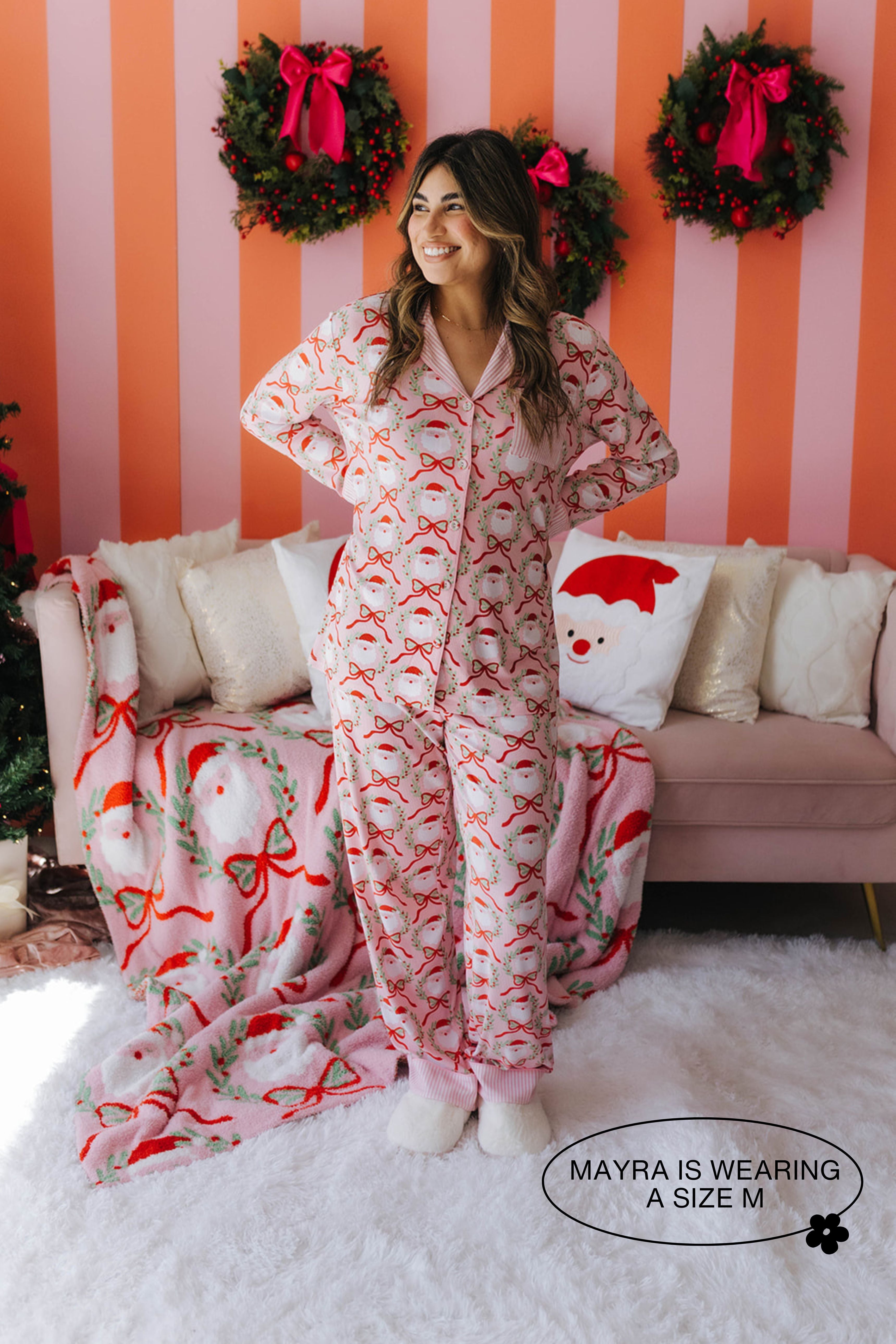 Woman wearing a festive pajama set in a room with Christmas decorations.