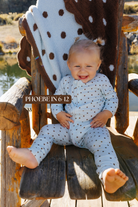 Sizing photo: Phoebe in 6-12 months wearing blue with brown polka dots baby zip pajamas.