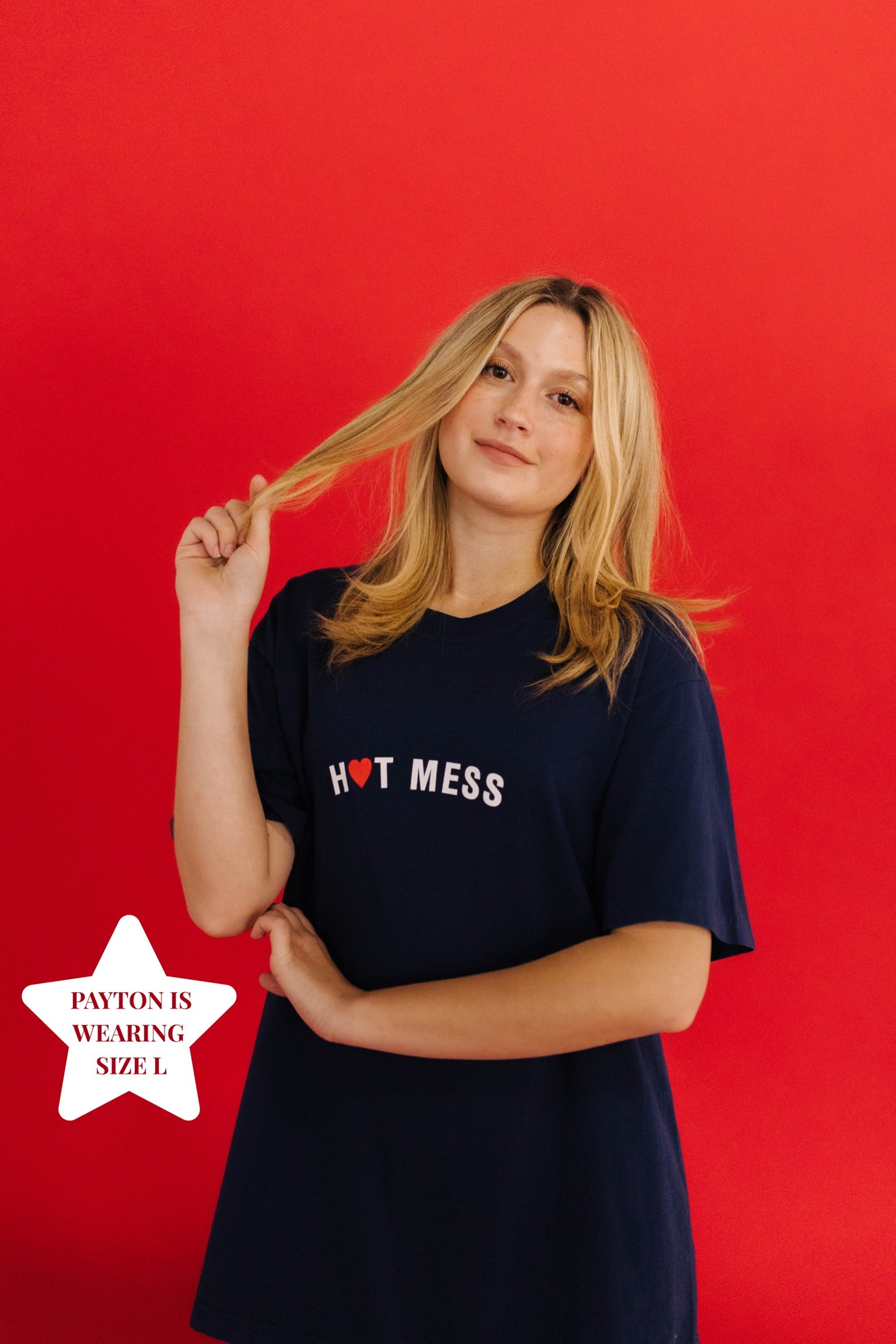 Woman wearing a navy t-shirt with 'Hot Mess' text against a red background