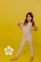 Young girl wearing a brunch pj set on a yellow background