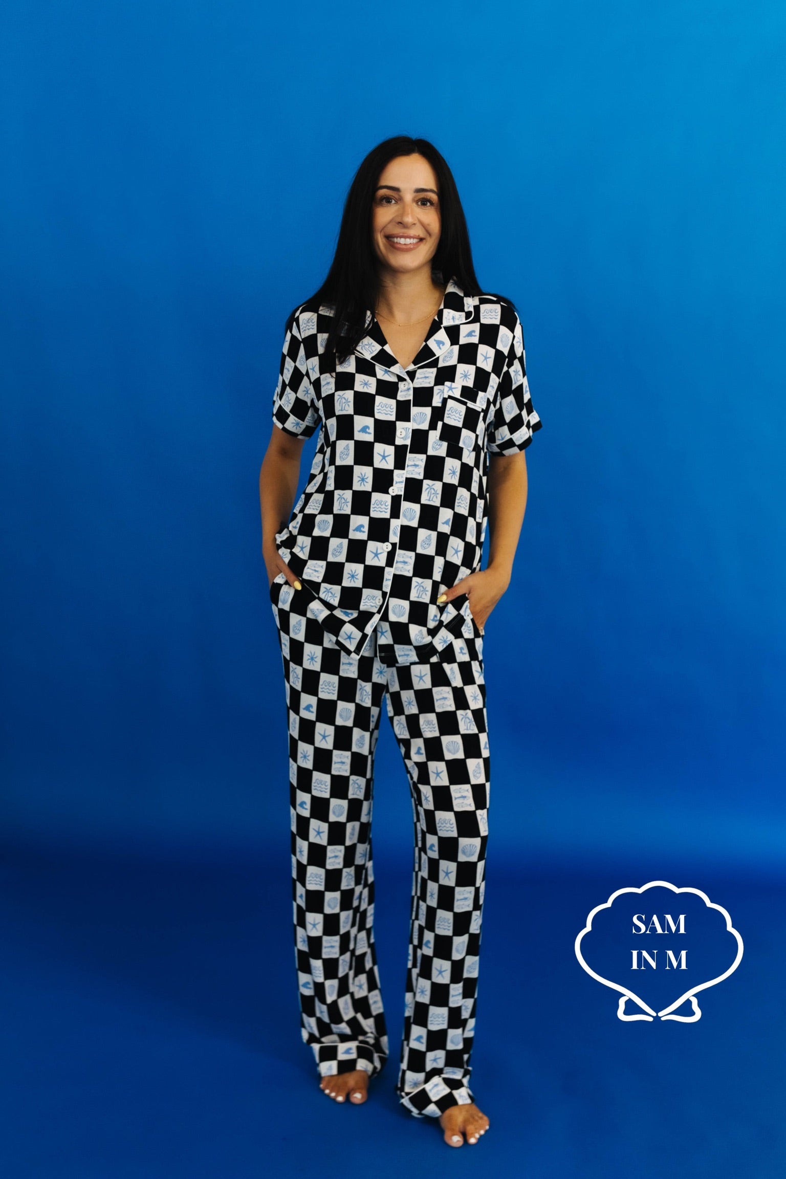 Person wearing a black and white checkered outfit against a blue background with - Sam in M
