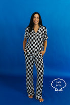 Person wearing a black and white checkered outfit against a blue background with - Sam in M