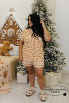 Woman in a pajama set standing in a festive room with Christmas decorations.