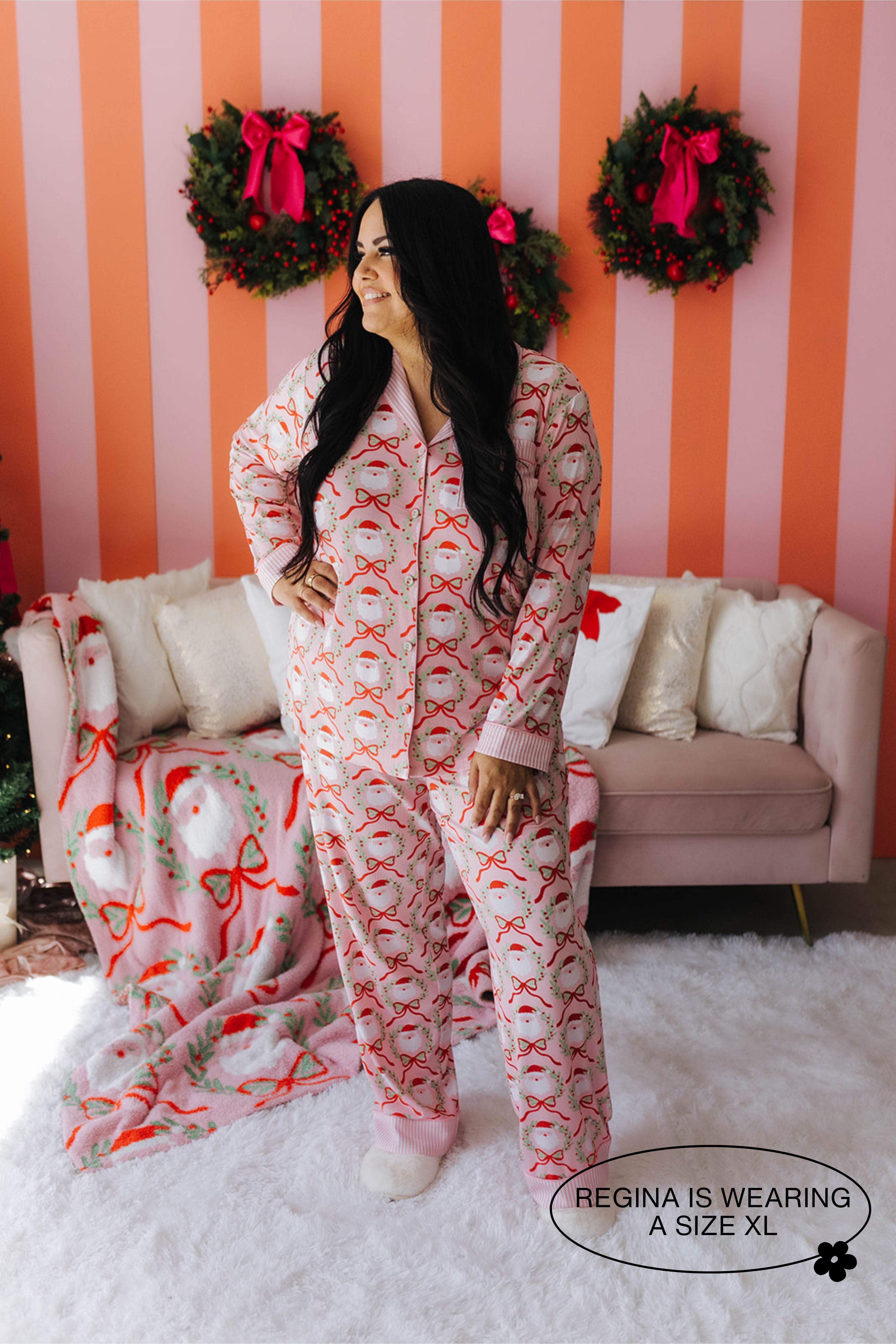 Woman wearing a festive onesie in a room with striped walls and Christmas wreaths.