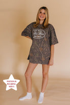 girl in camo tee that says hot mess in front of a cream background