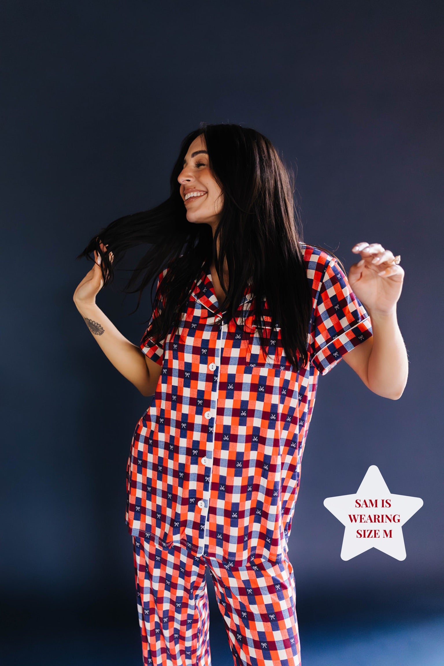Girl smiling wearing a red and blue gingham pj set on blue background 