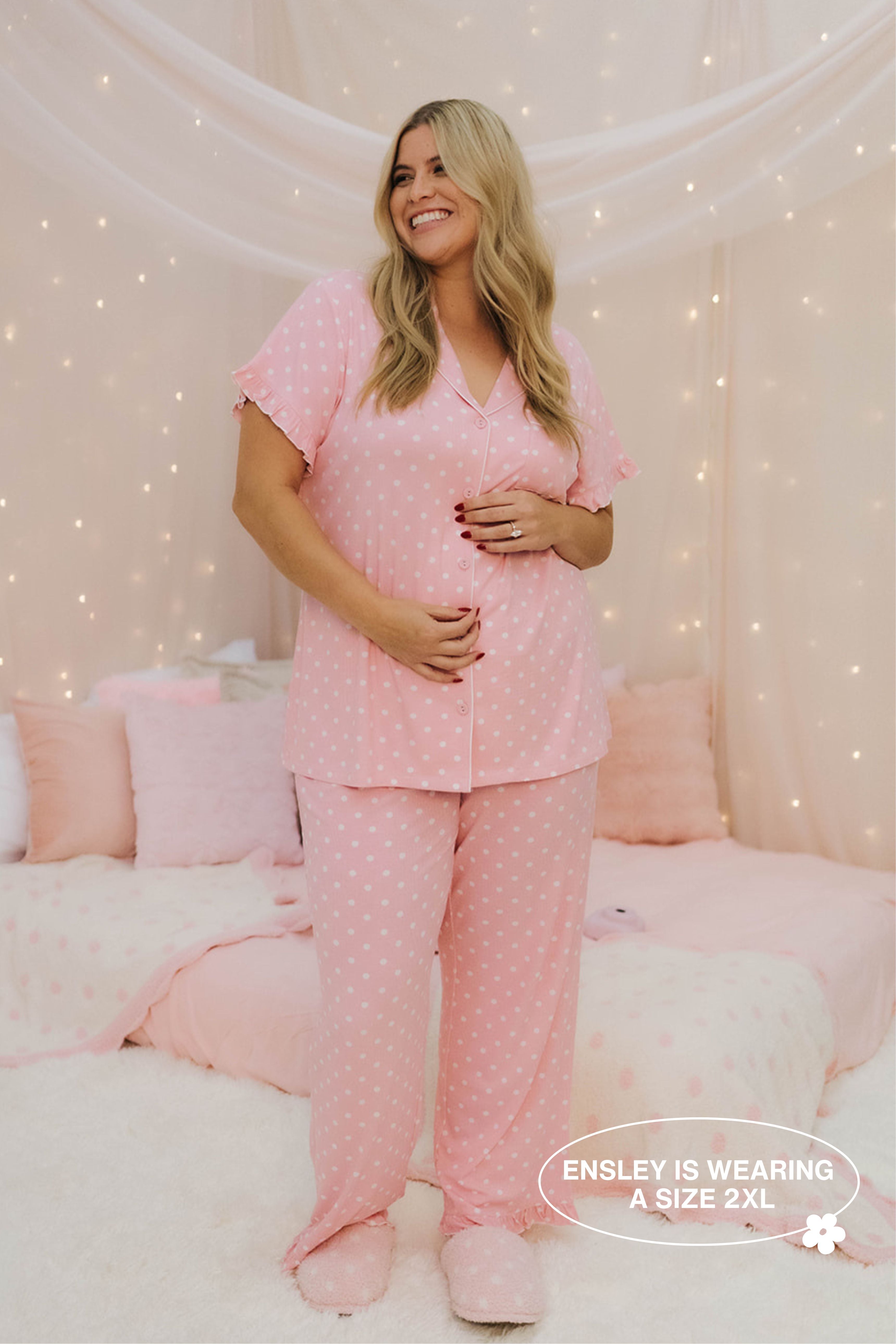 Woman wearing pink polka dot pajamas in a cozy bedroom setting.