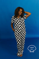 Woman wearing a black and white checkered outfit against a blue  background - Taren in S