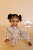 Child wearing a patterned onesie on a beige background