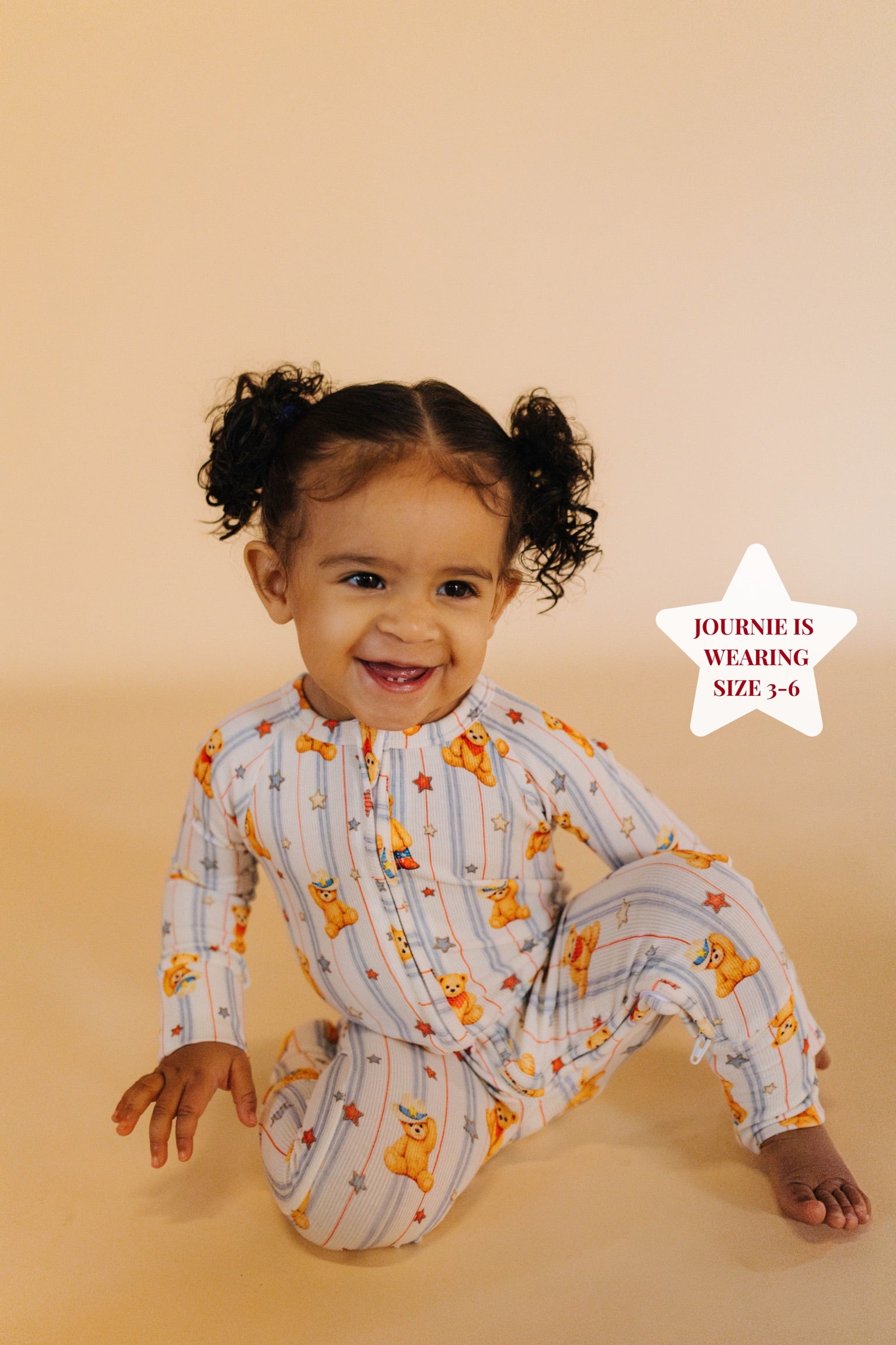 Child wearing a patterned onesie on a beige background