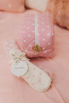 Pink polka dot bag with matching pink plush socks on a soft pink background