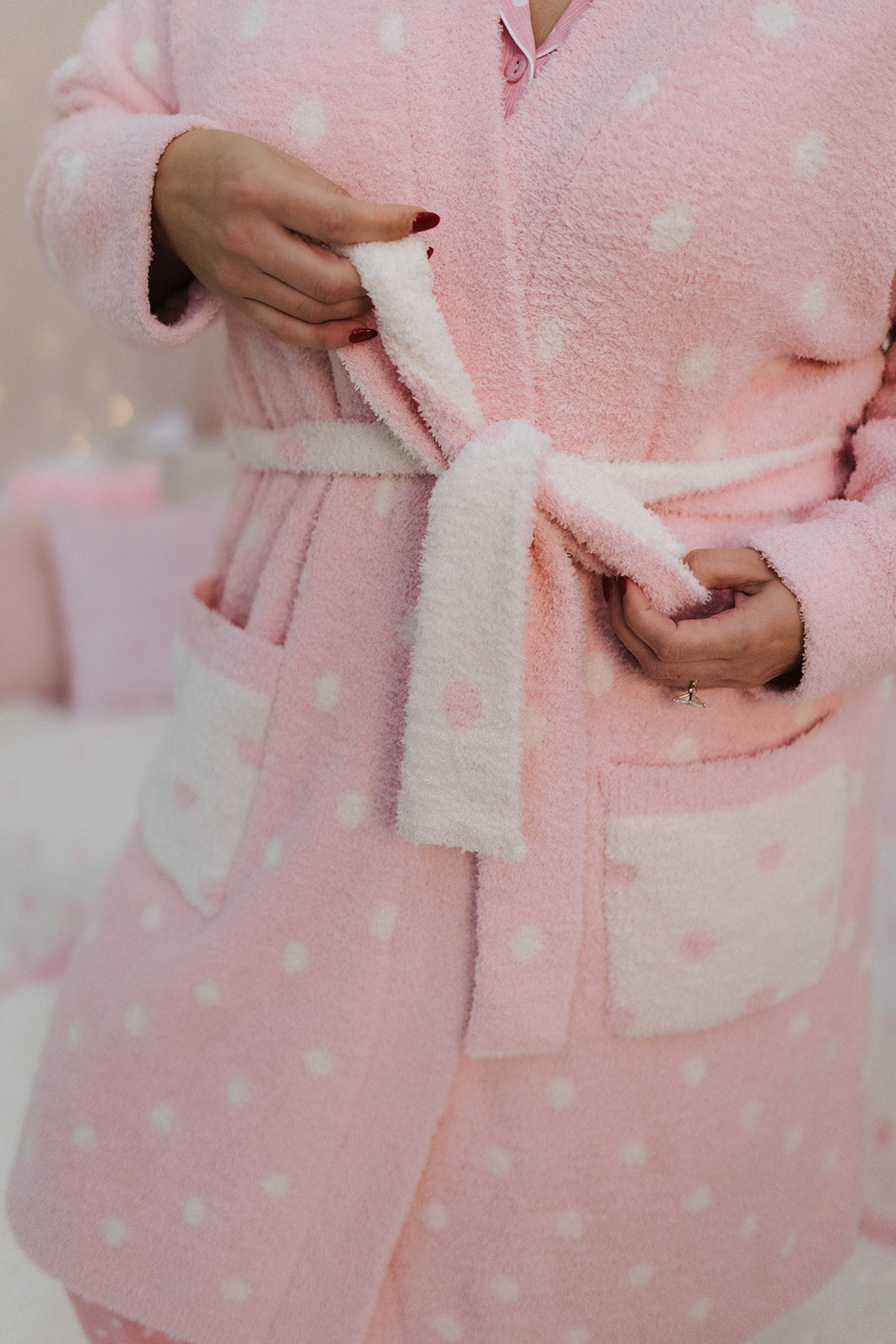 Person wearing a pink robe with white polka dots and a matching belt.