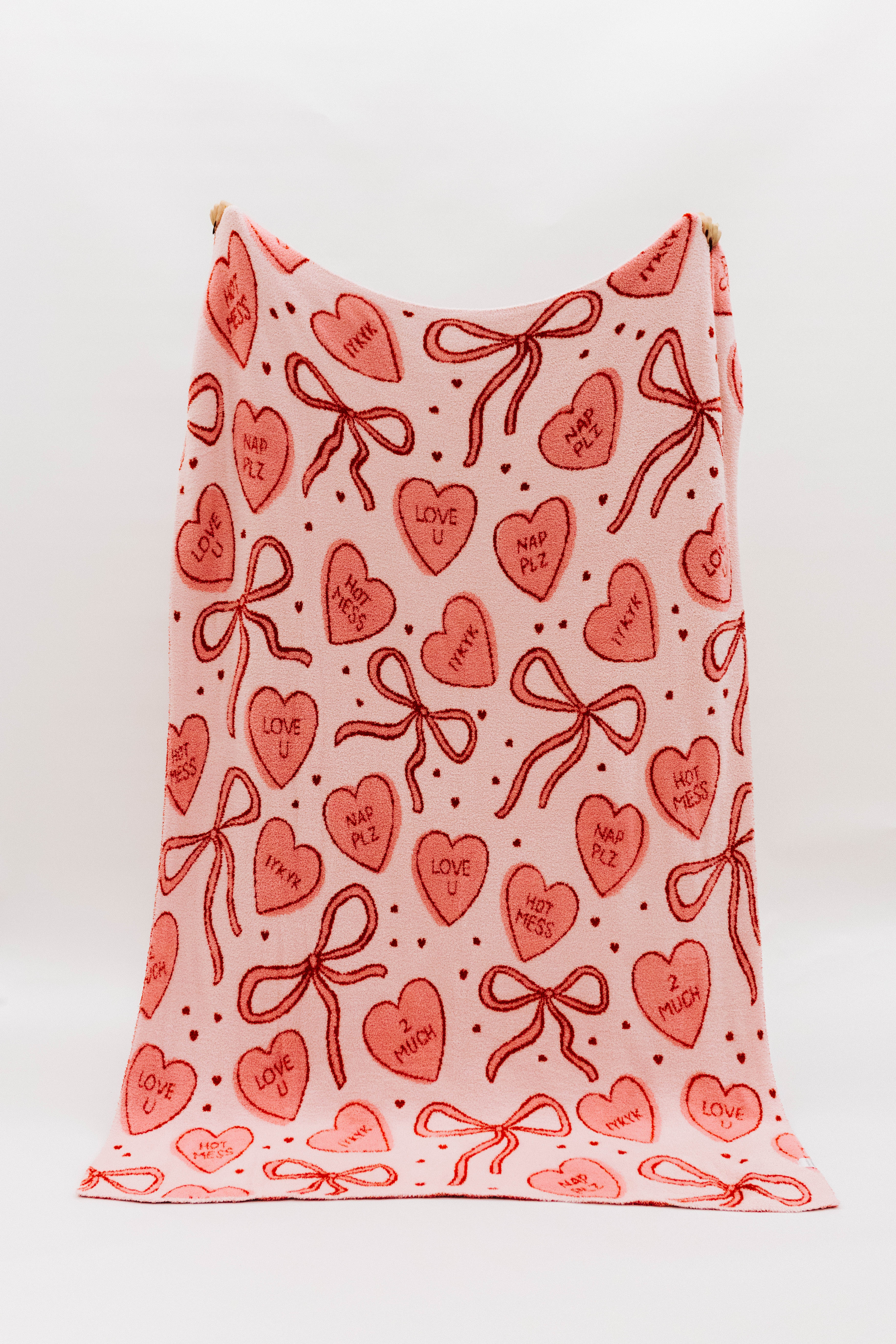 Pink blanket showing candy hearts and bows 