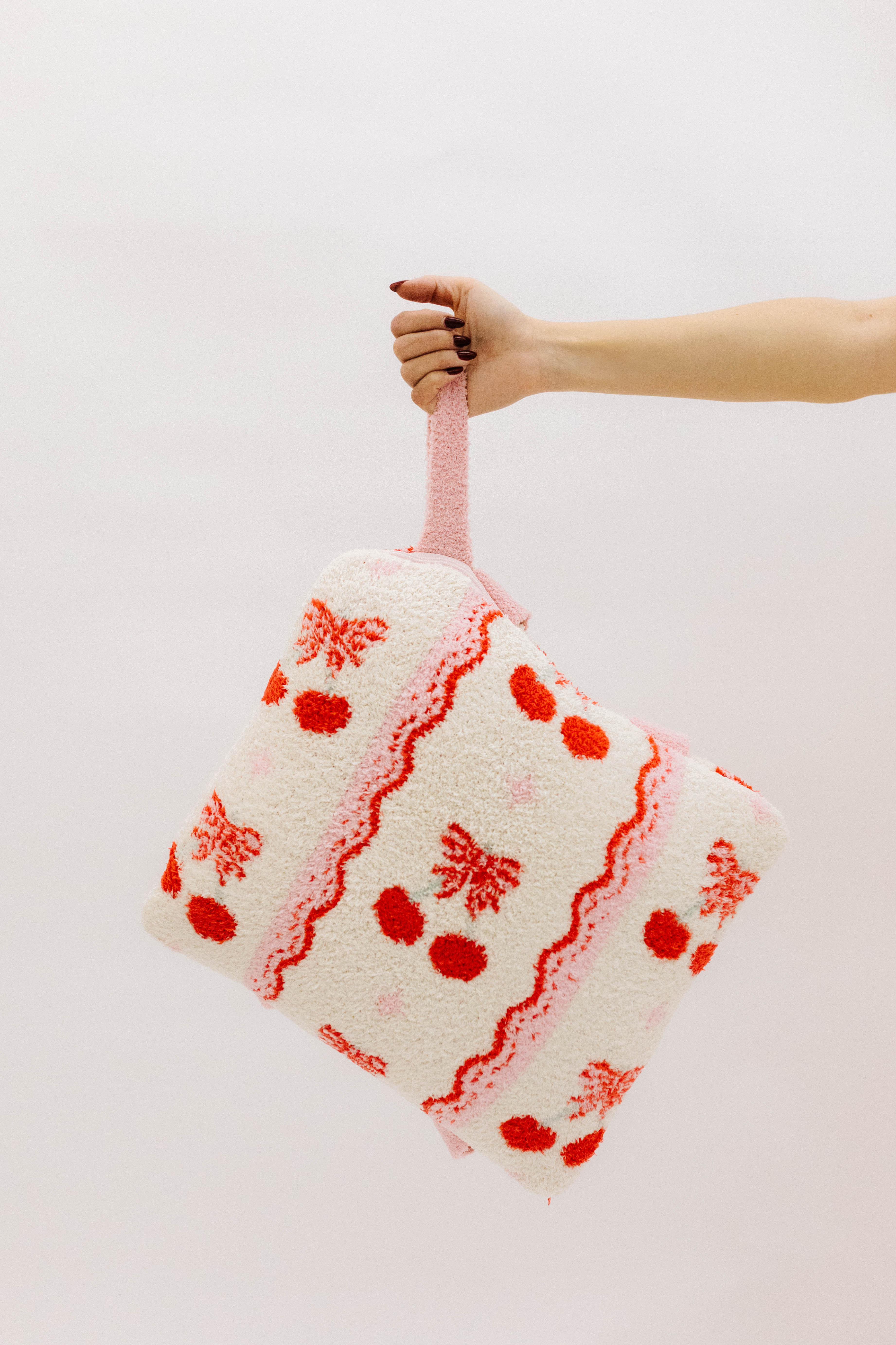 holding the cherry quillow by the wristlet