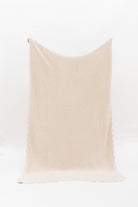 Beige ribbed blanket with scalloped edges on a white background