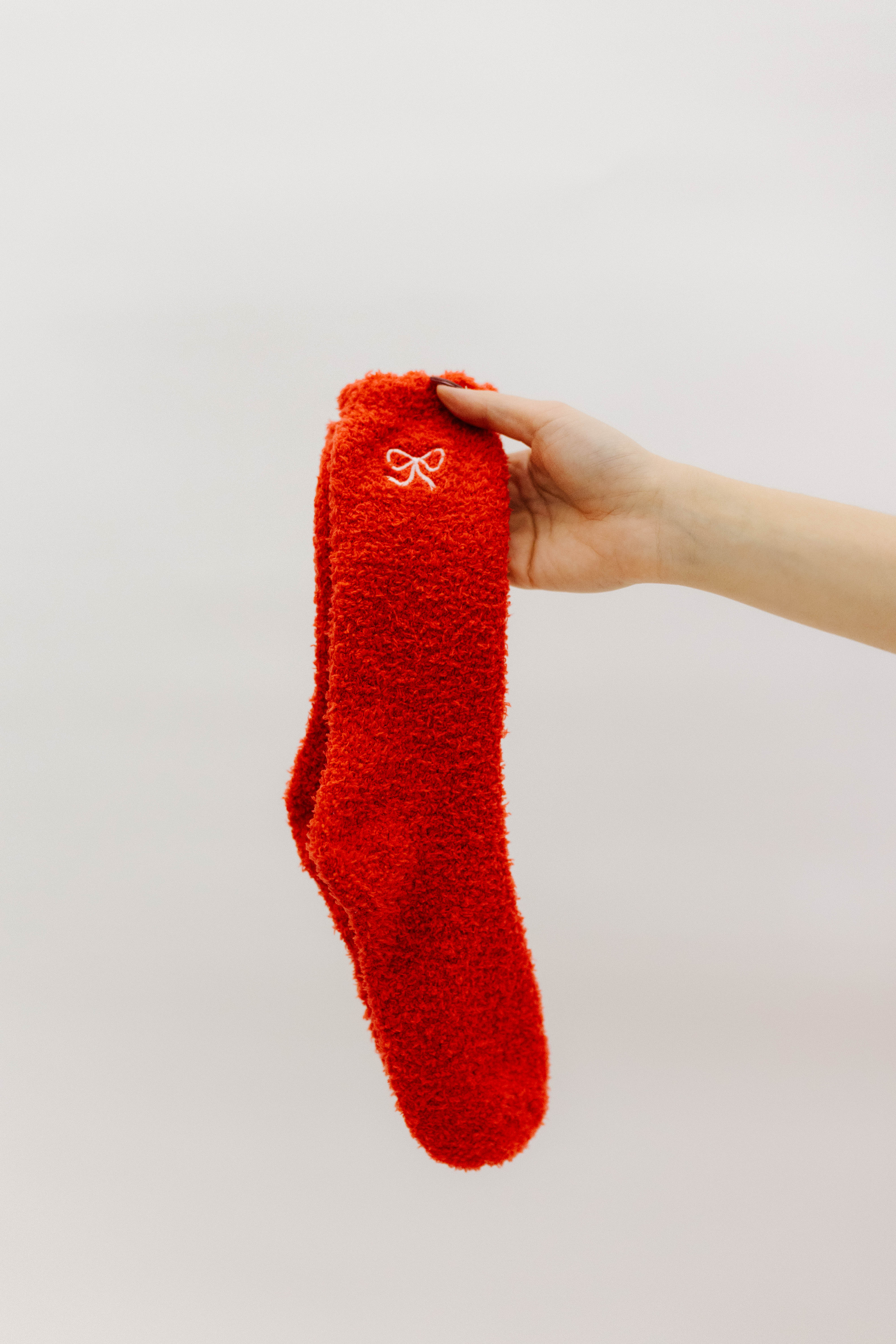 Red fuzzy sock held by a hand against a white background