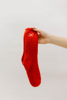Red fuzzy sock held by a hand against a white background