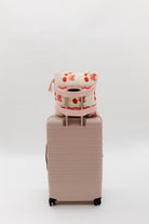 cherry quillow styled on a beis suitcase
