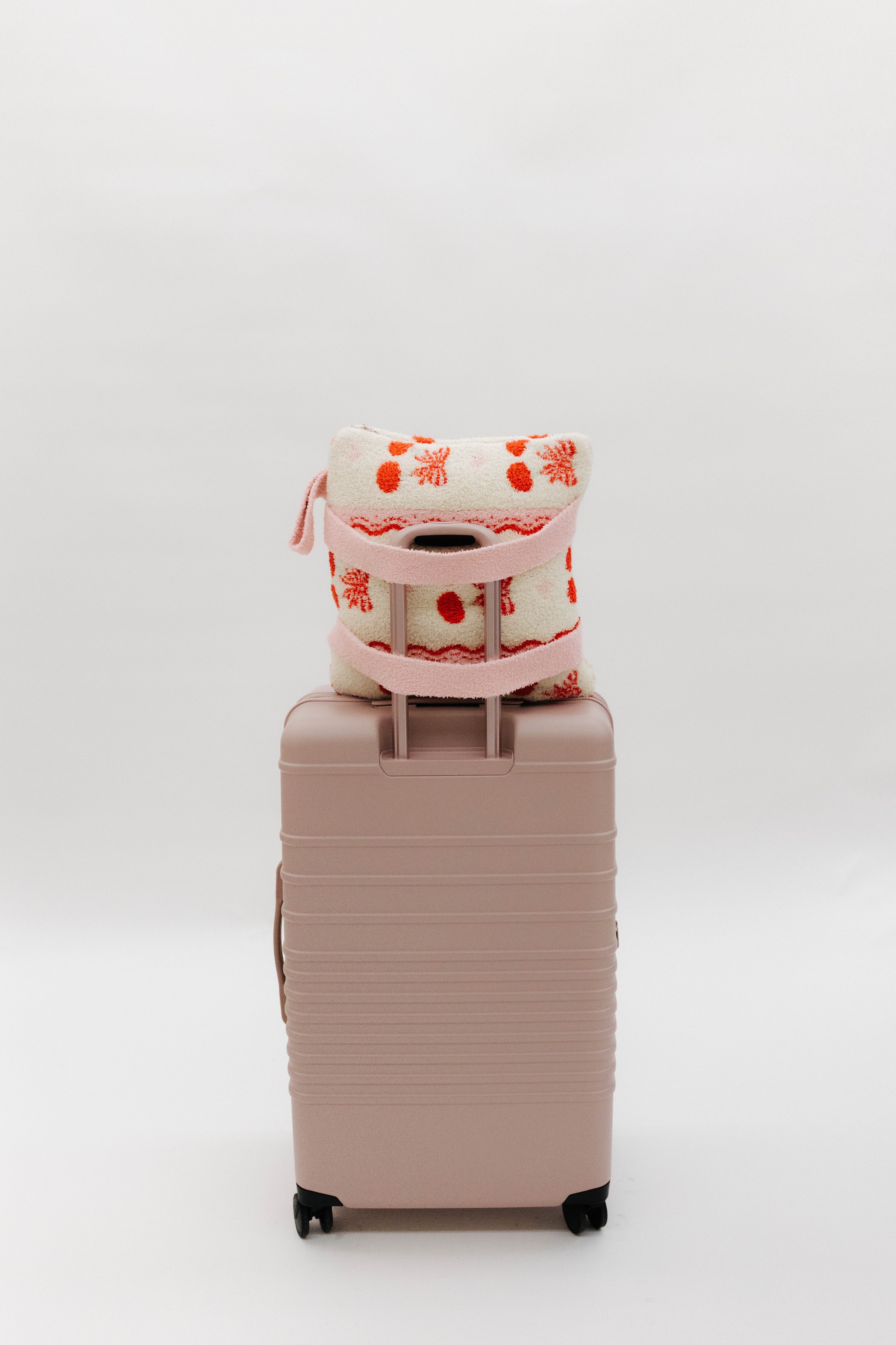 cherry quillow styled on a beis suitcase
