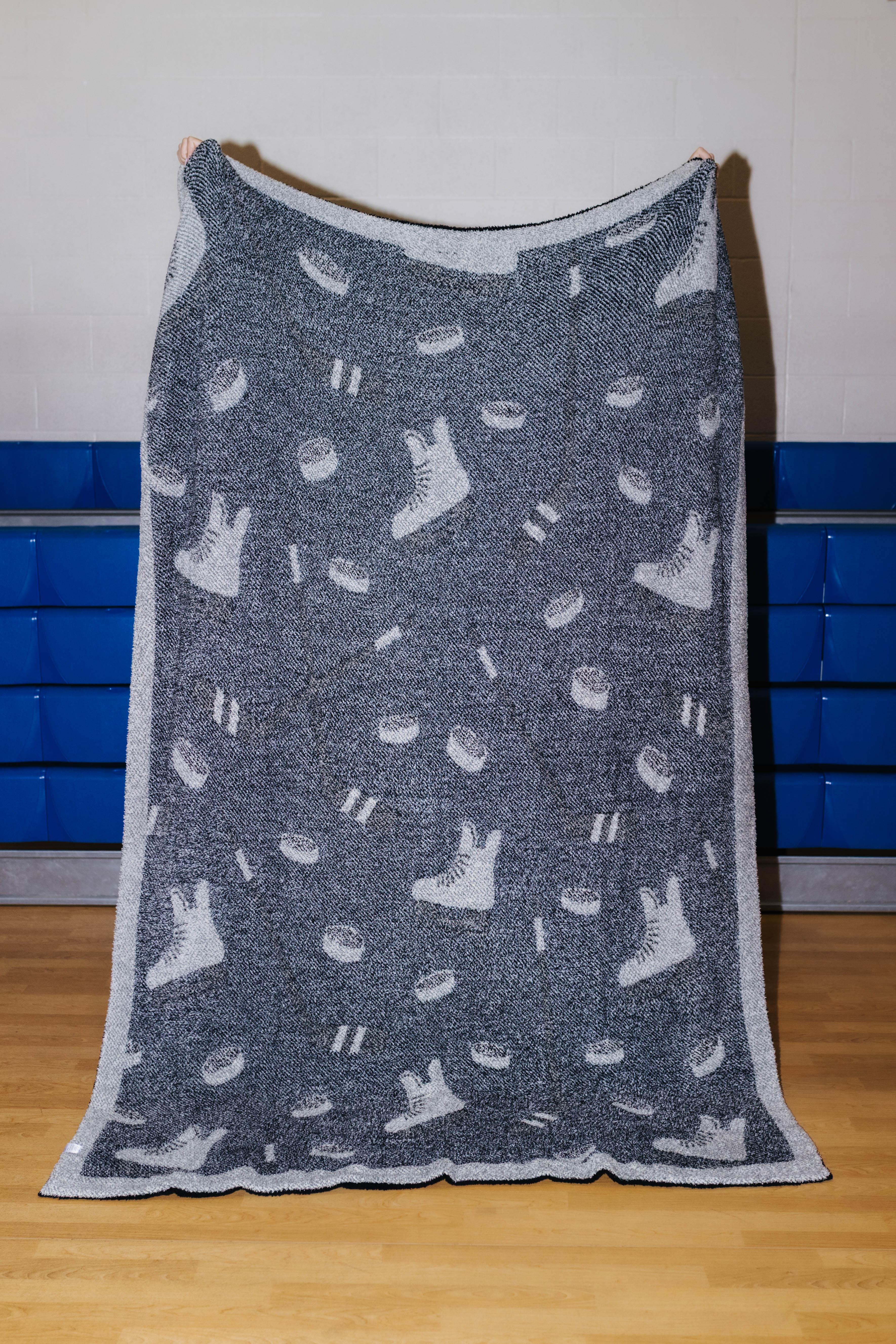 Back of hockey blanket showing mostly black with the skates and pucks being white
