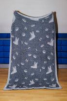Back of hockey blanket showing mostly black with the skates and pucks being white