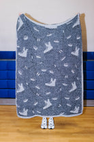 Back side of the hockey blanket being held up showing mostly black background with hockey sillhouetes