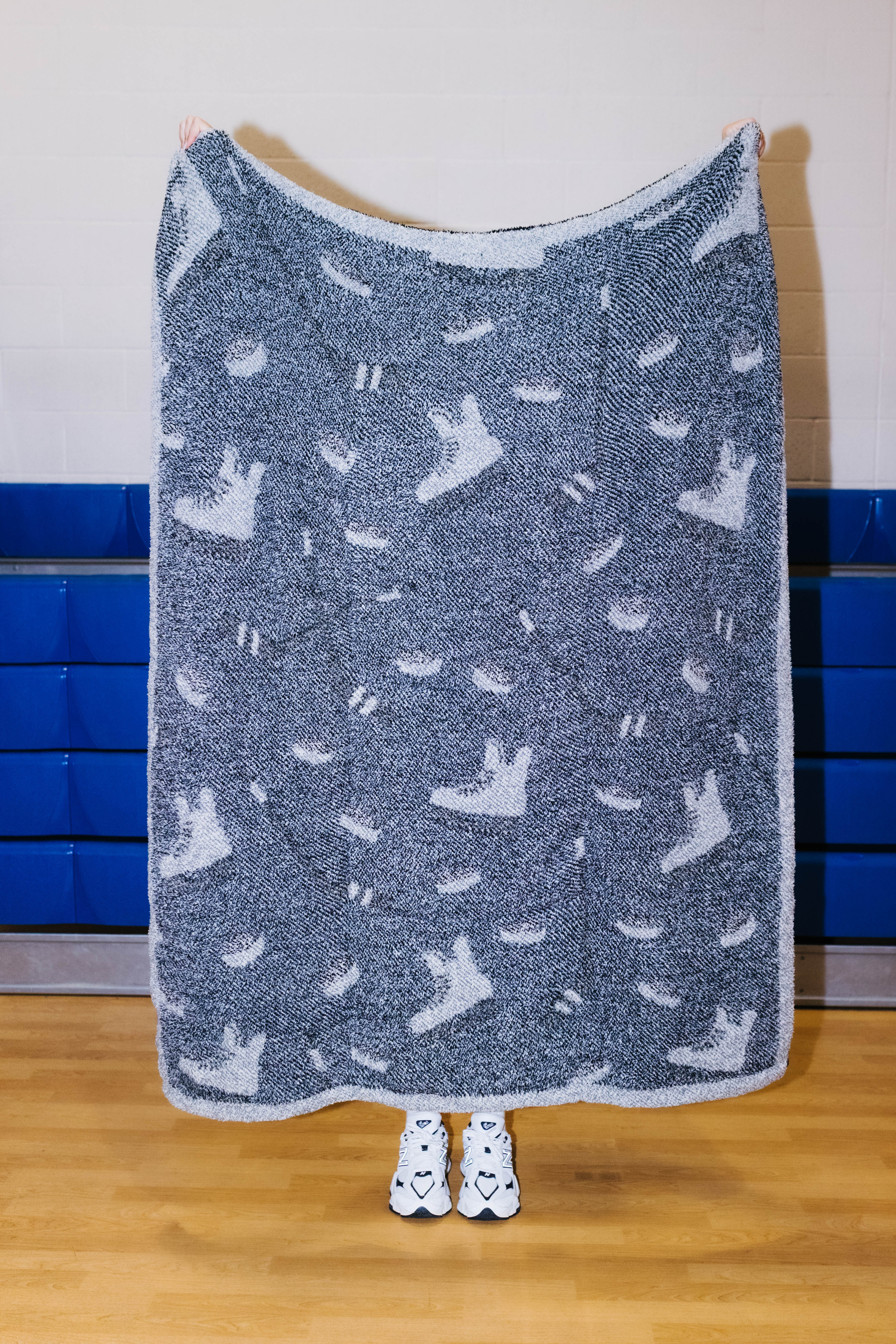 Back side of the hockey blanket being held up showing mostly black background with hockey sillhouetes