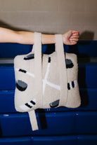 A person's arm and hand holding the quillow by the backpack straps. 