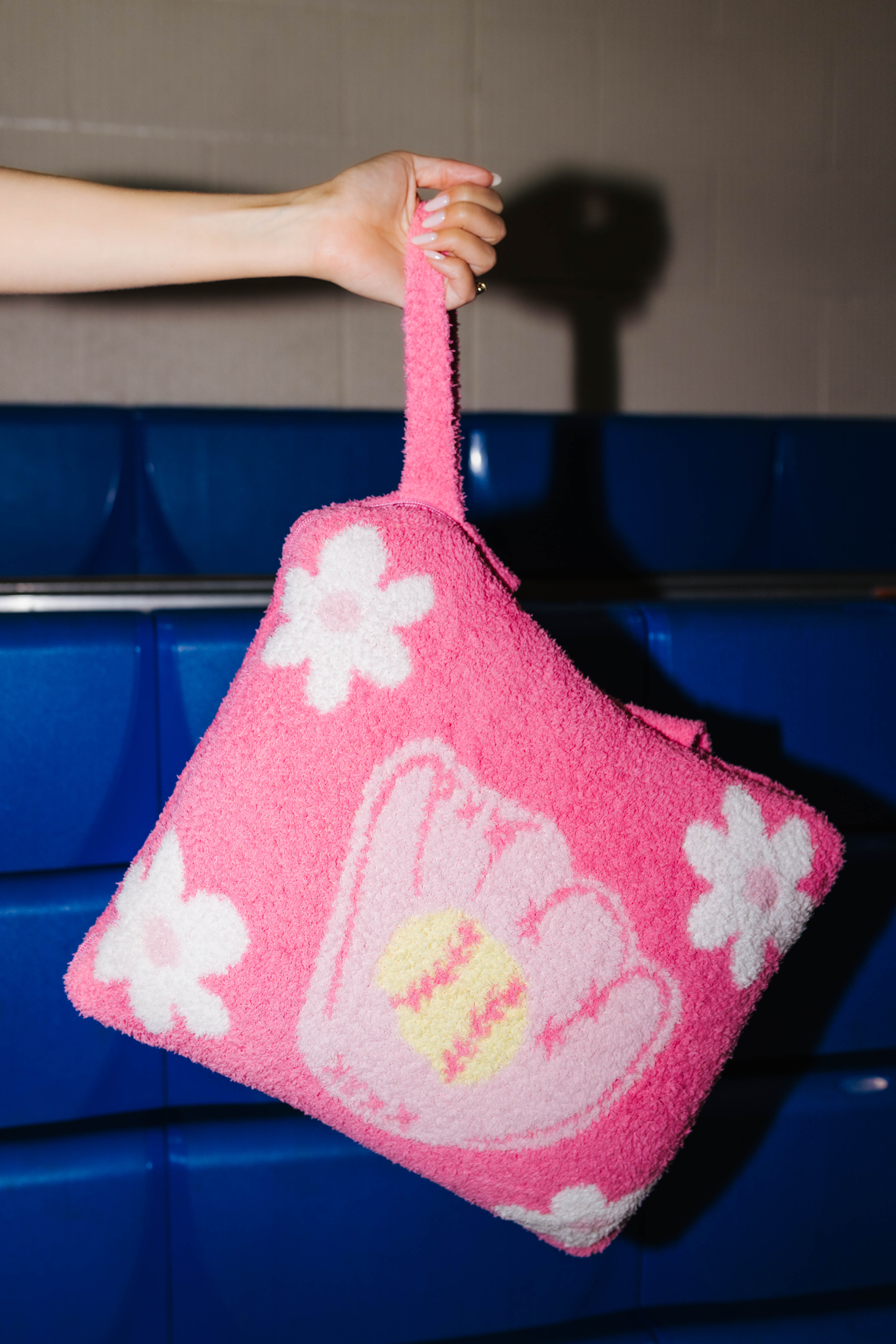 Holding the quillow by the wristlet straps showing the flower and softball design