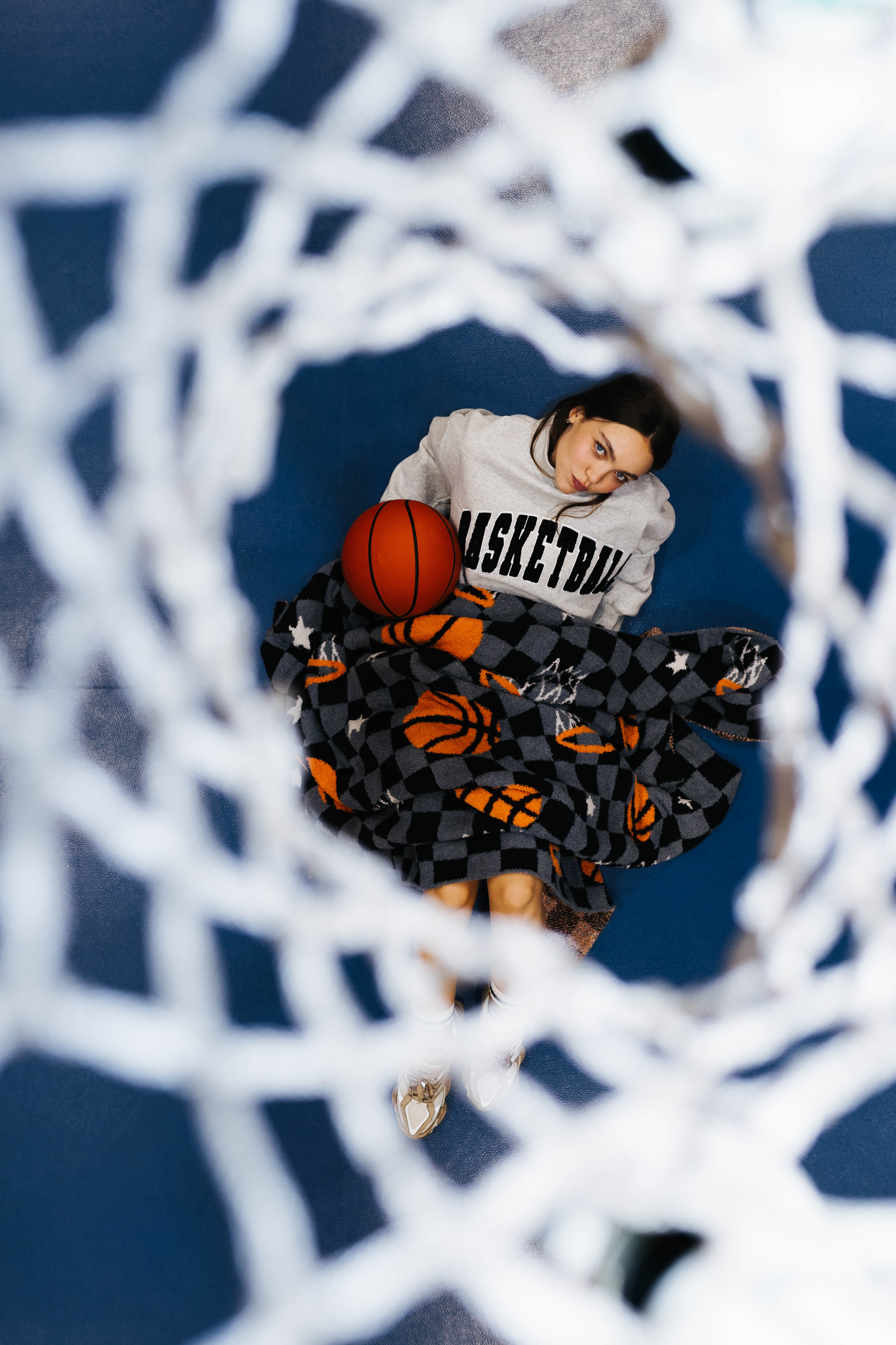 girl under the hoop in a basketball sweatshirt, holding a basketball blanket nd basketball
