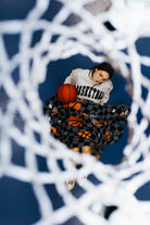 girl under the hoop in a basketball sweatshirt, holding a basketball blanket nd basketball