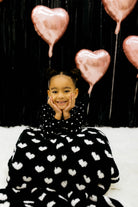 Child with the black side of the blanket draped on her lap