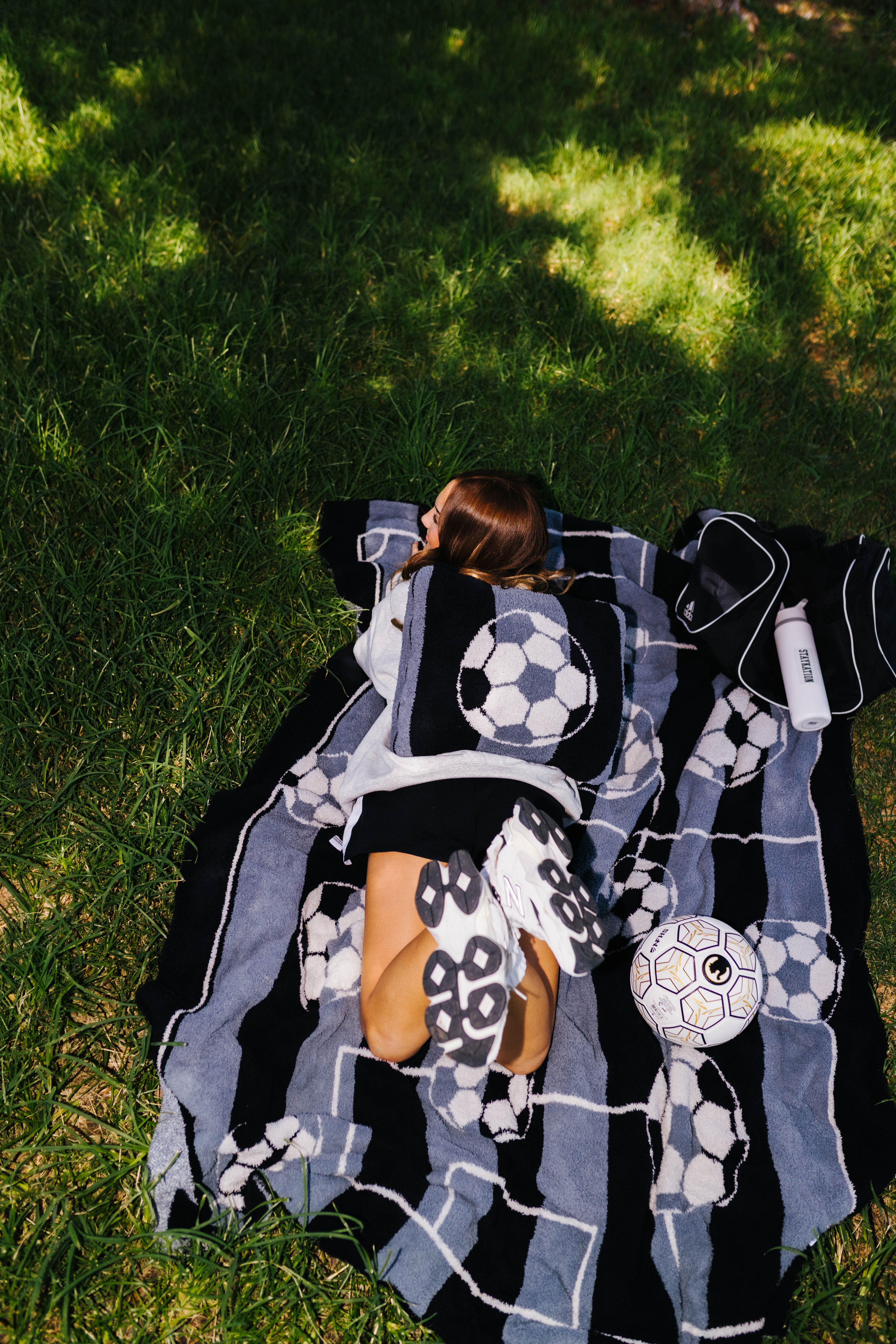 girl laying on the soccer ball blanket with a soccer ball quillow on her back
