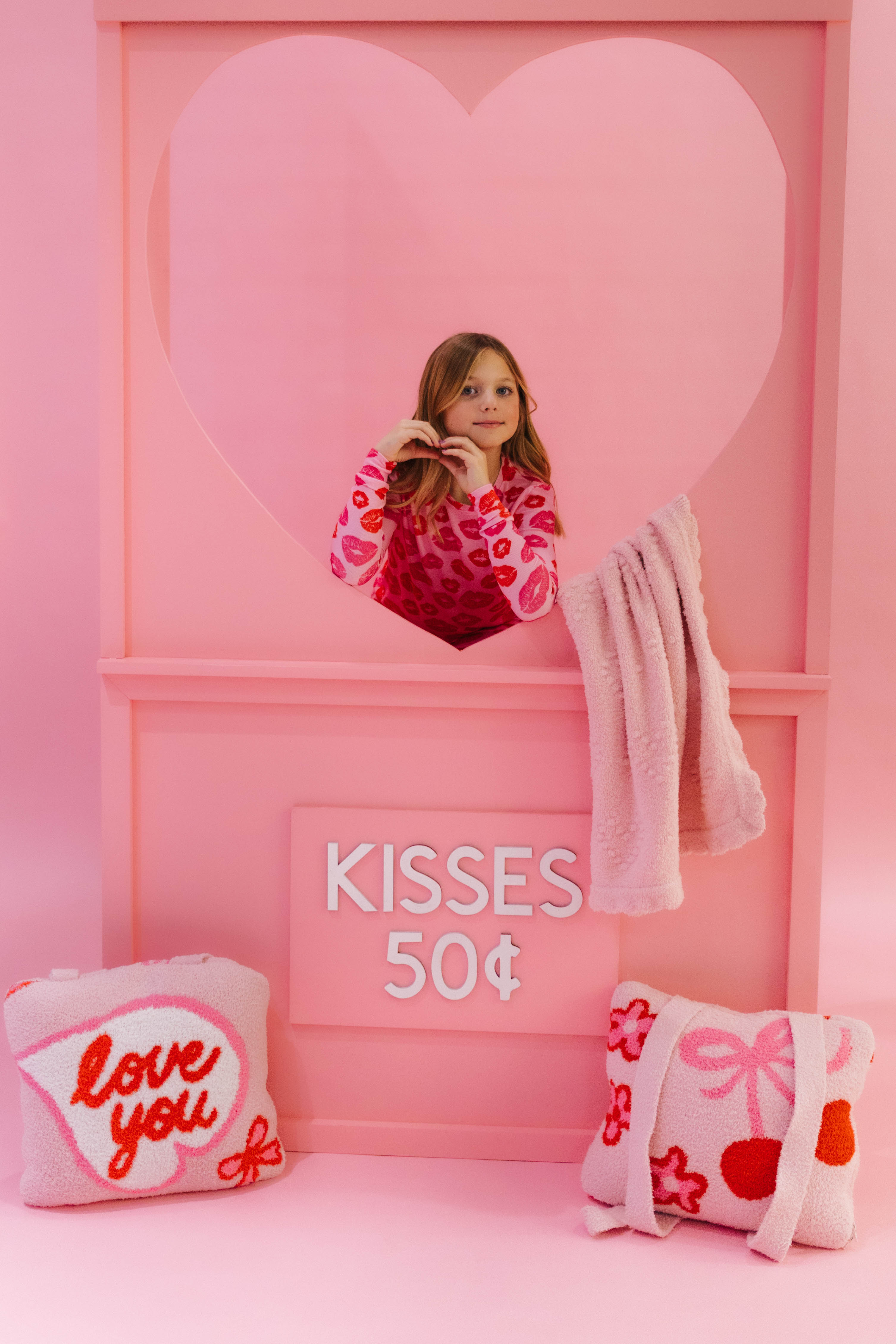 child doing heart hands with love you quillows on the ground