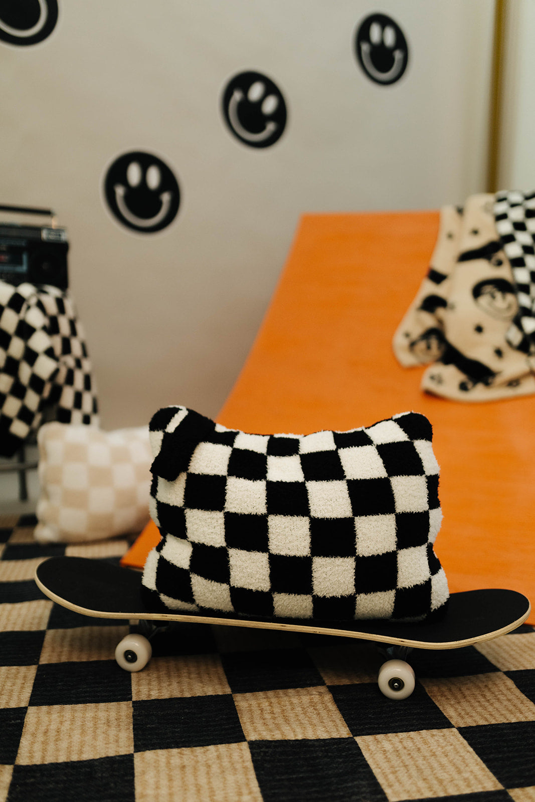 Checkered pillow on a skateboard with a checkered floor and wall decorations in the background