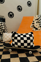 Checkered pillow on a skateboard with a checkered floor and wall decorations in the background