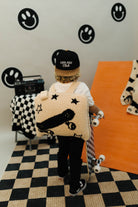 Person holding a patterned quillow in a room with checkered floor and wall decorations.