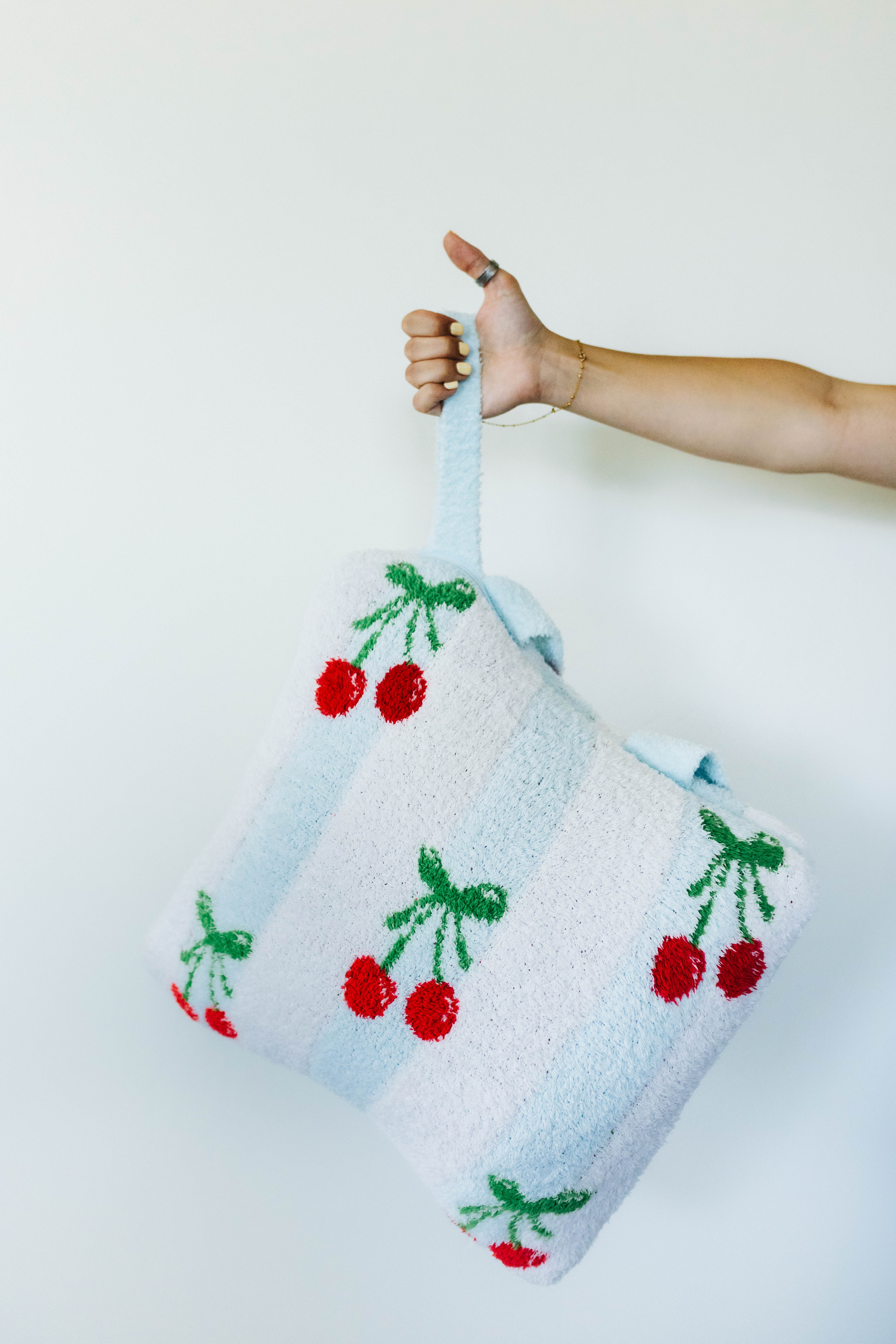 Quillow with cherry pattern held by a person on a white background