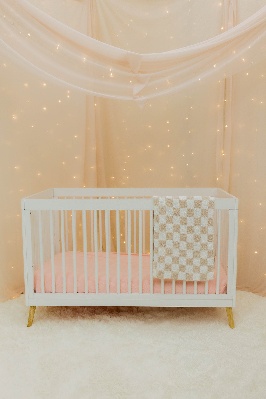 White crib with checkered blanket in a softly lit room