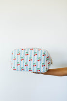 Fabric pouch with cherry pattern held by a person against a white background