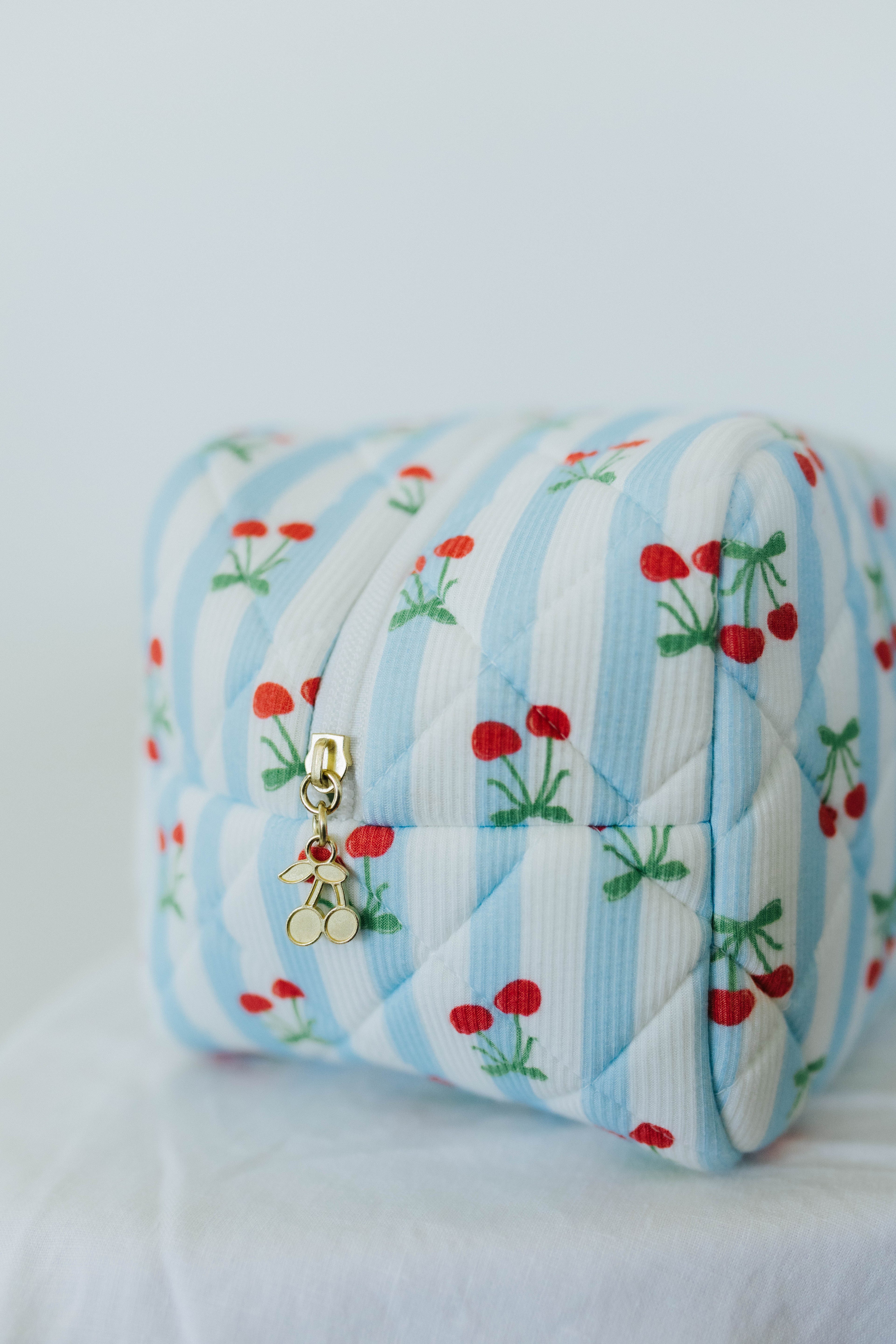 Quilted cosmetic bag with cherry pattern on a white background