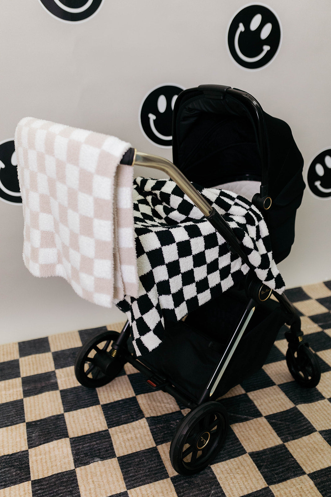 Black stroller with checkered blanket on a checkered floor