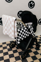 Black stroller with checkered blanket on a checkered floor