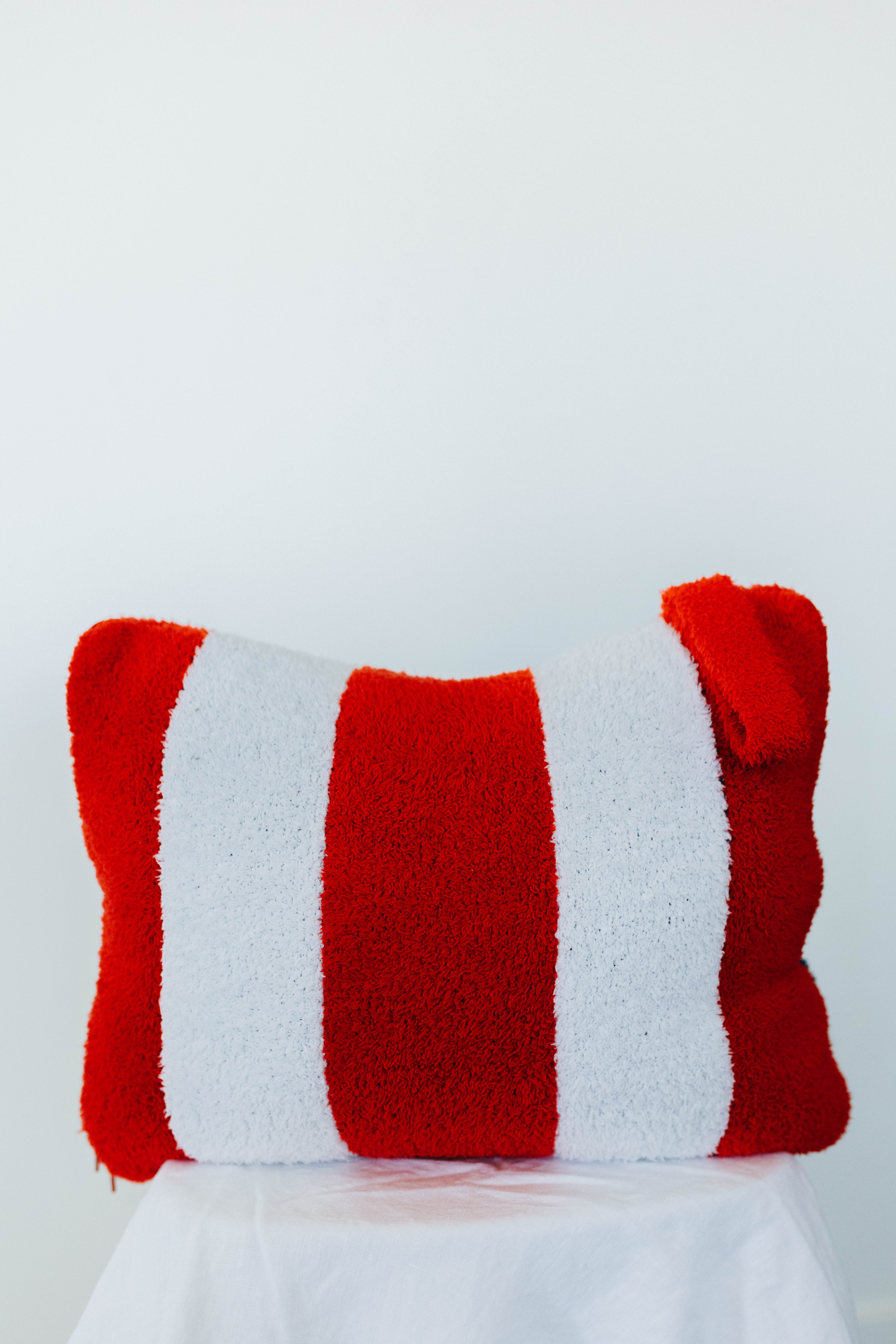 Red and white striped quillow on a white background