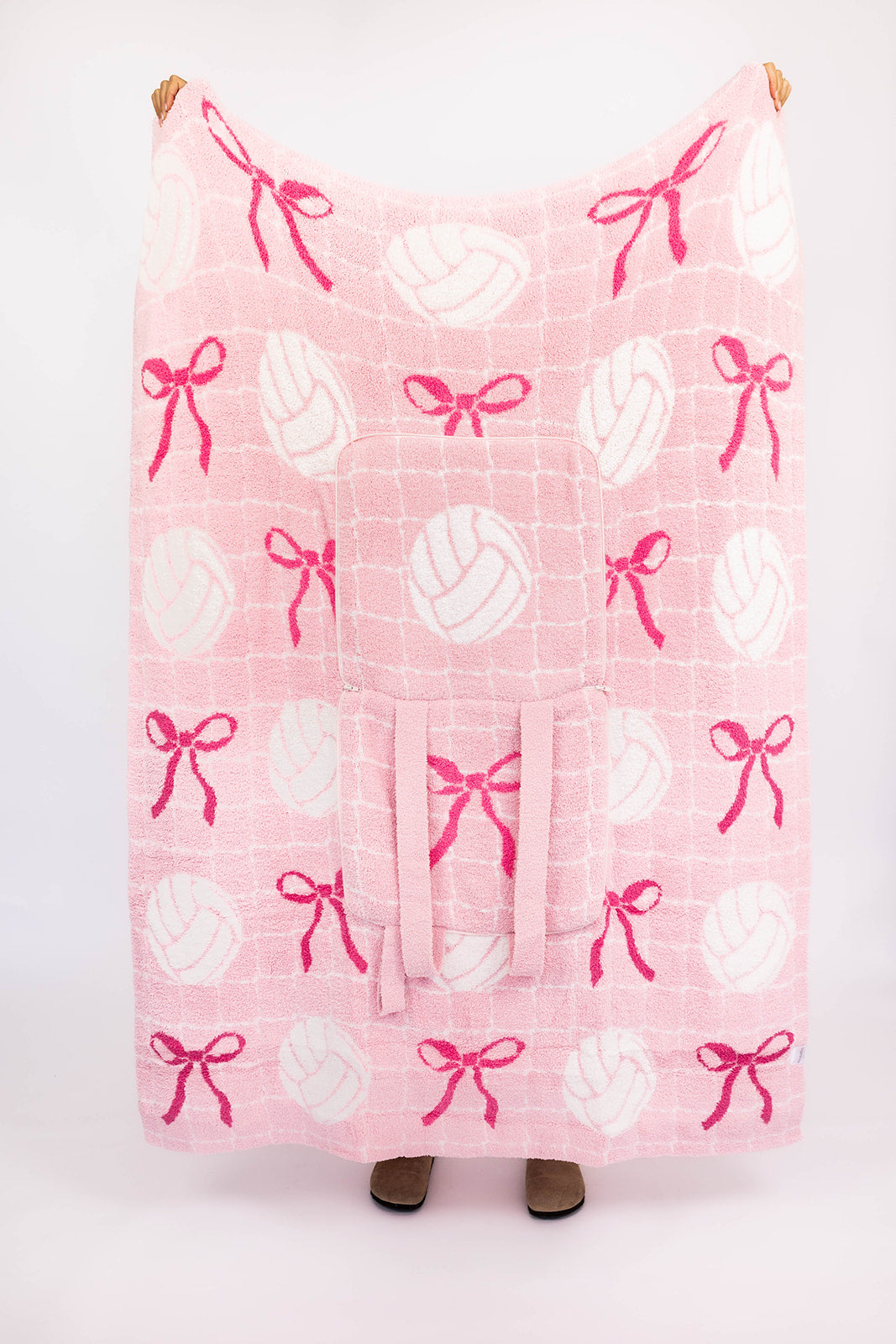 Pink blanket with white volleyballs and pink bows on a white background