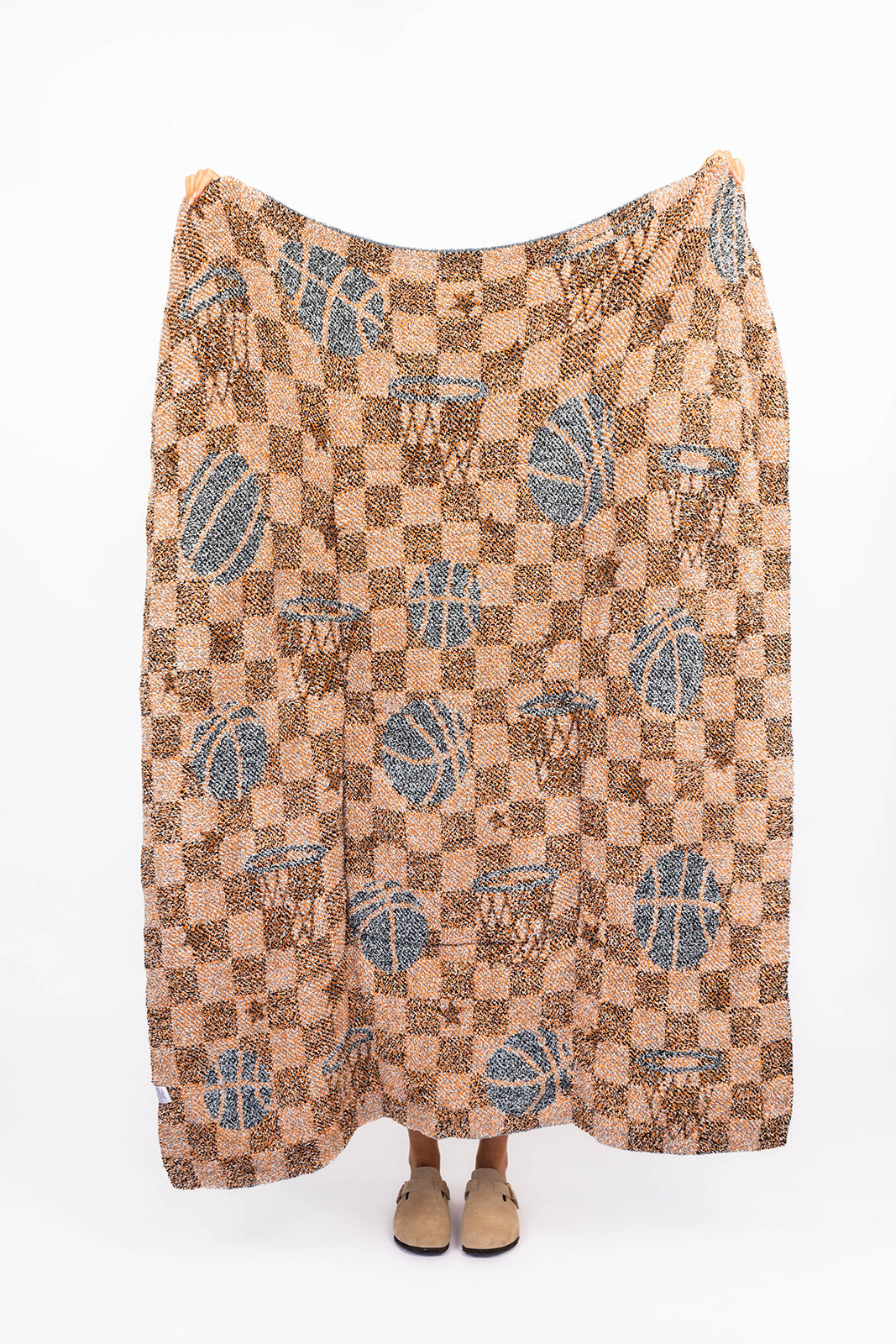 Patterned basketball blanket draped over a person on a white background