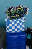 Blue checkered towel on a blue suitcase with 'Gamer Zone' sign in the background