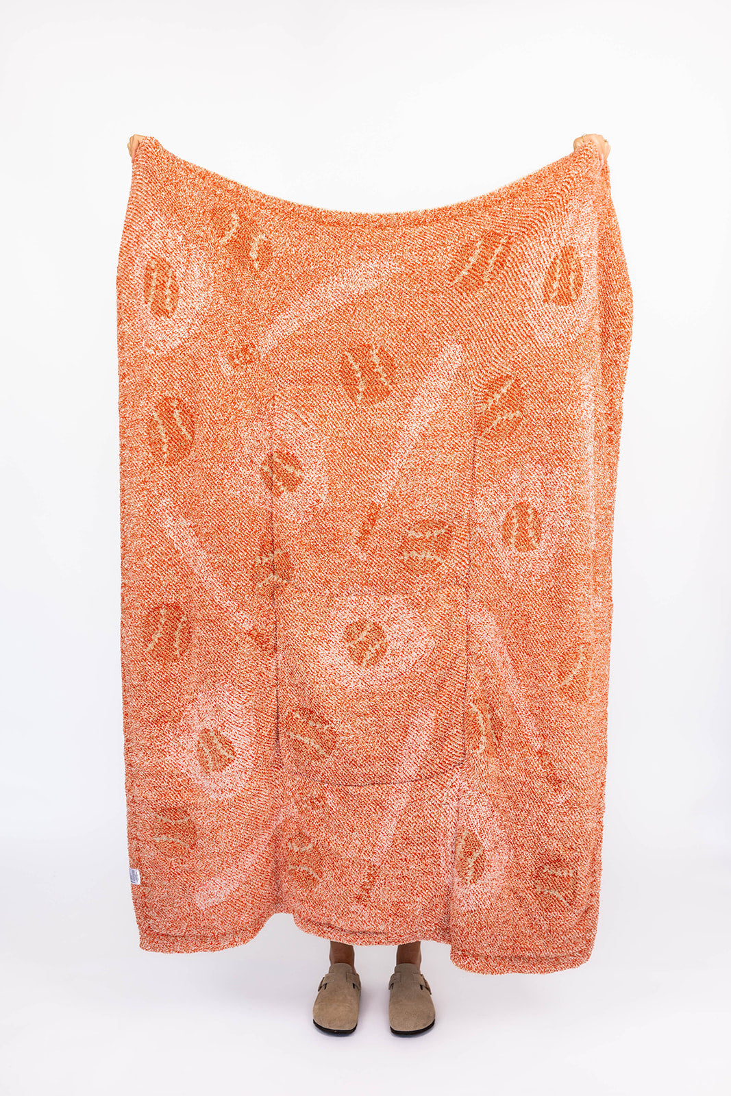 Orange blanket with white baseball design on a white background