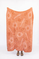 Orange blanket with white baseball design on a white background